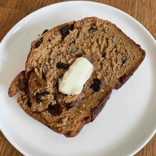 Slice of trail mix bread with a pat of butter