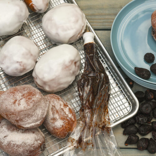 Fig sufganiyot recipe fried doughnuts and fig preserves in a pastry bag with whole mission figs nearby.