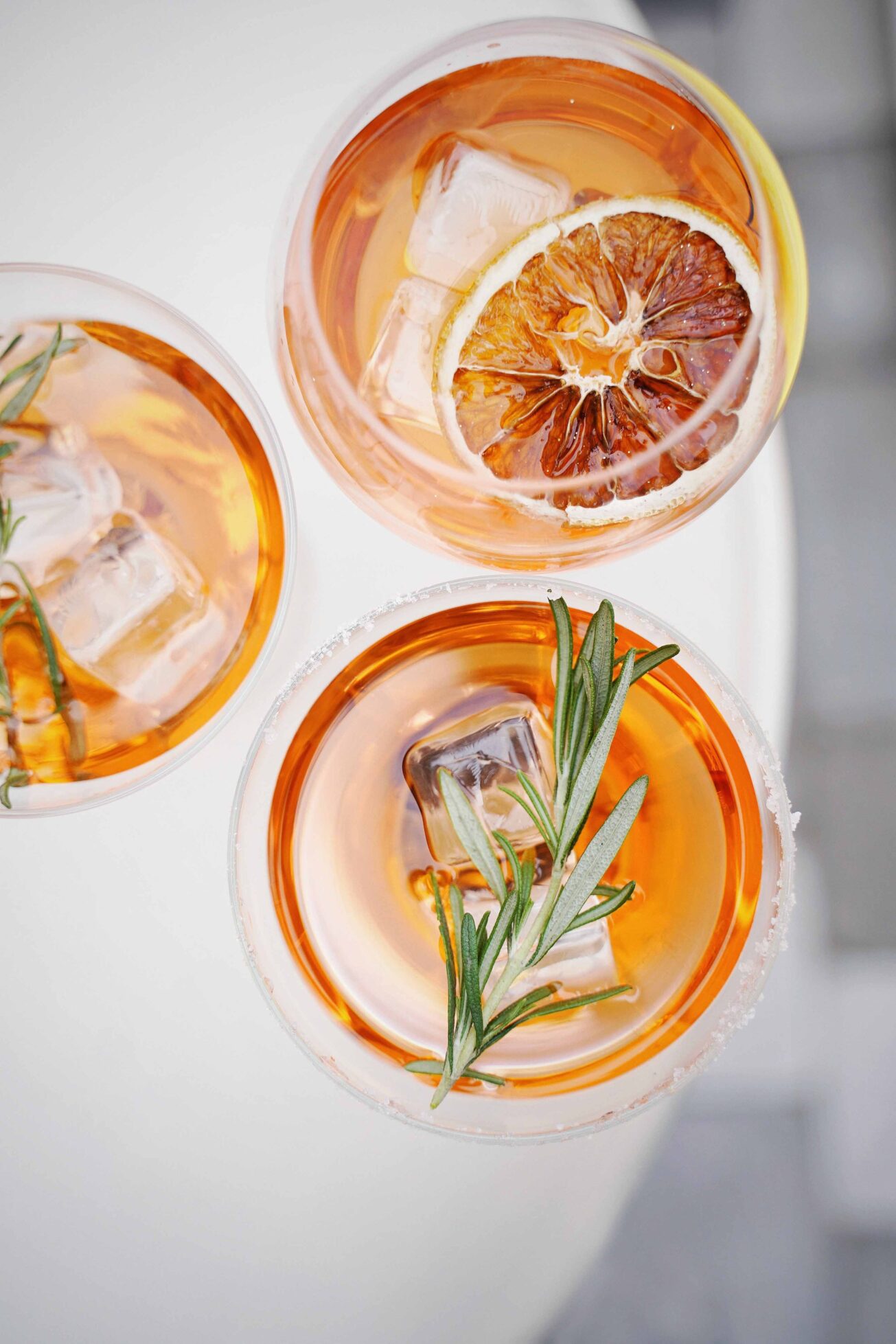 Fig vodka cocktail recipe showing overhead glasses with dried orange slices and rosemary.