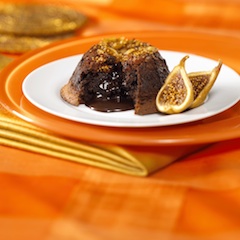 Warm chocolate cake recipe made in the "lava" cake style, full of mission fig goodness oozing out, on a white plate set off against an orange background