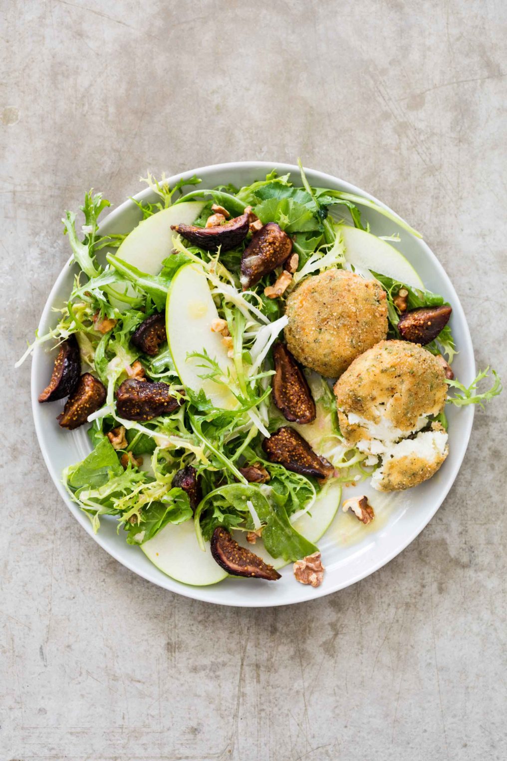 Baked goat cheese tops an apple salad with figs, and walnuts for a center stage salad.
