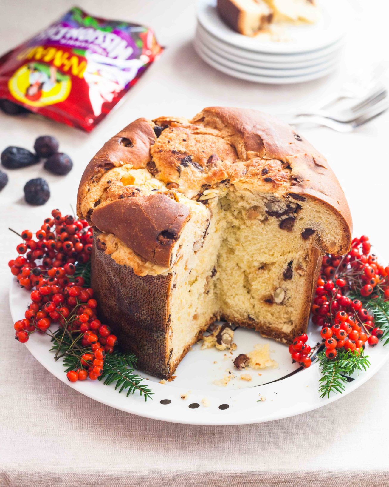 Dark chocolate panettone bread with dried figs and decorative winter berries on a platter.