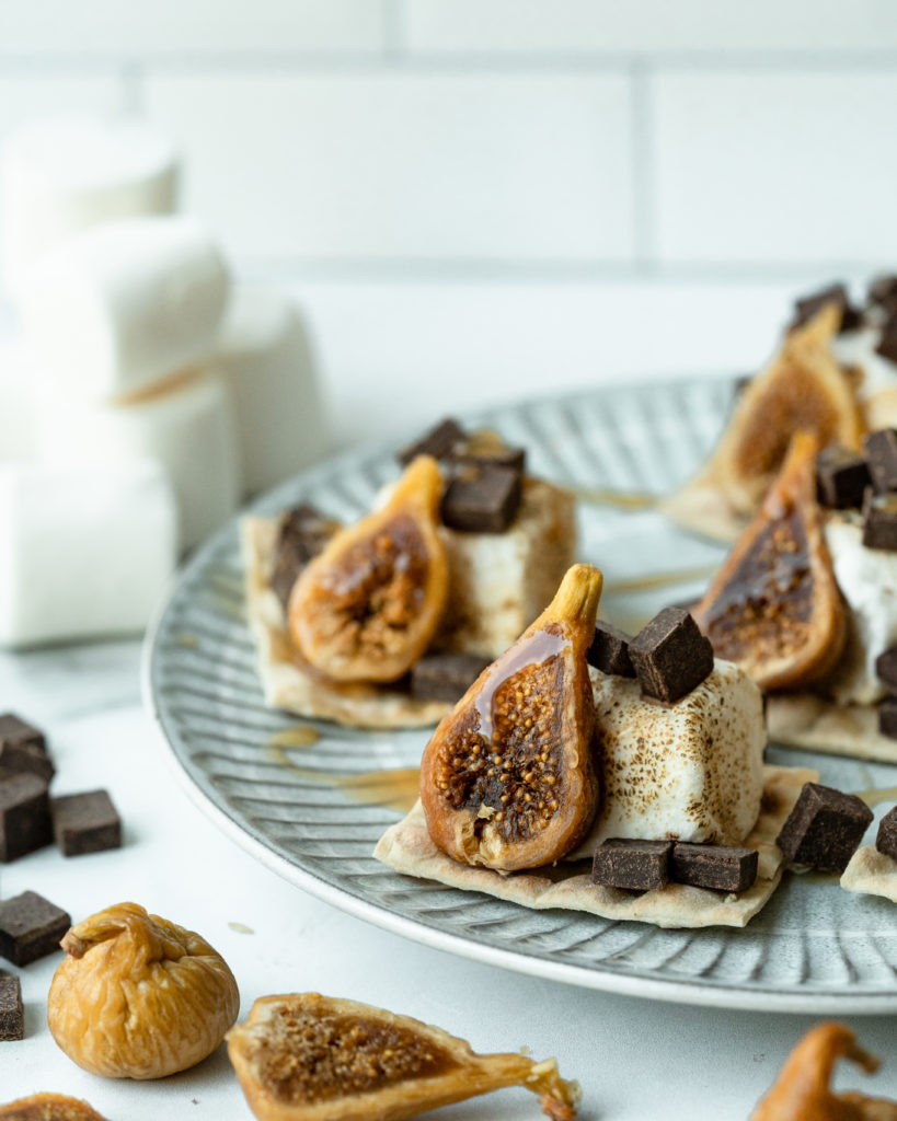 Lavash bread crackers on a platter with golden figs, honey, marshmallow, and chocolate.