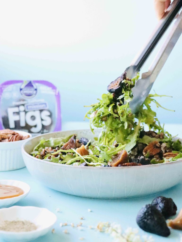 Tossing an arugula salad with figs 
