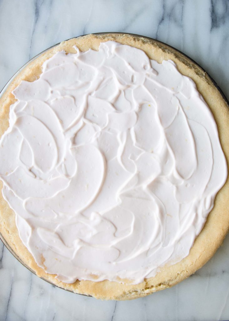 Greek yogurt spread onto a sugar cookie dough crust for fruit pizza