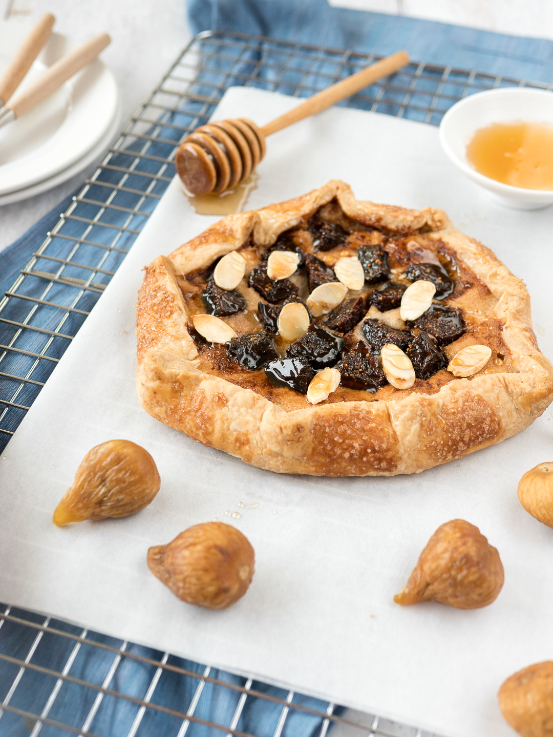 Fig galette on cutting board with golden figs scattered around it.