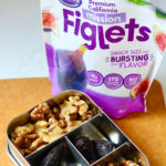 Bento box of walnuts and California Dried Figs and a bag of Orchard Choice Mission Figlets