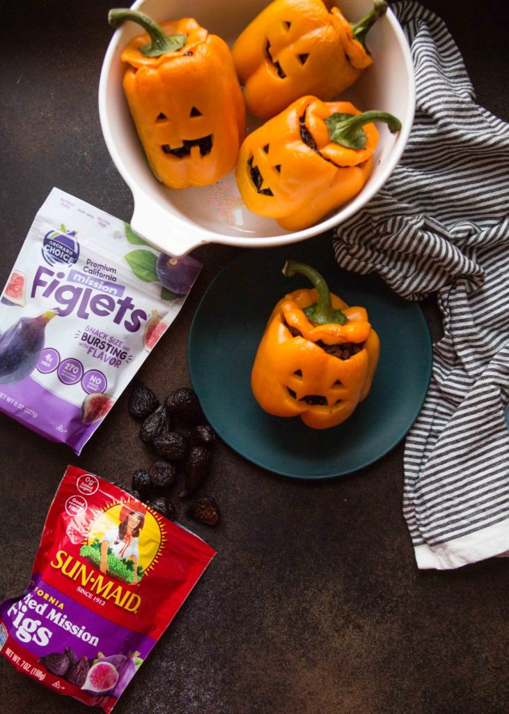 Jack O Lantern stuffed peppers  on a plate and in a casserole dish with bags of Orchard Choice and Sun-Maid FIgs.