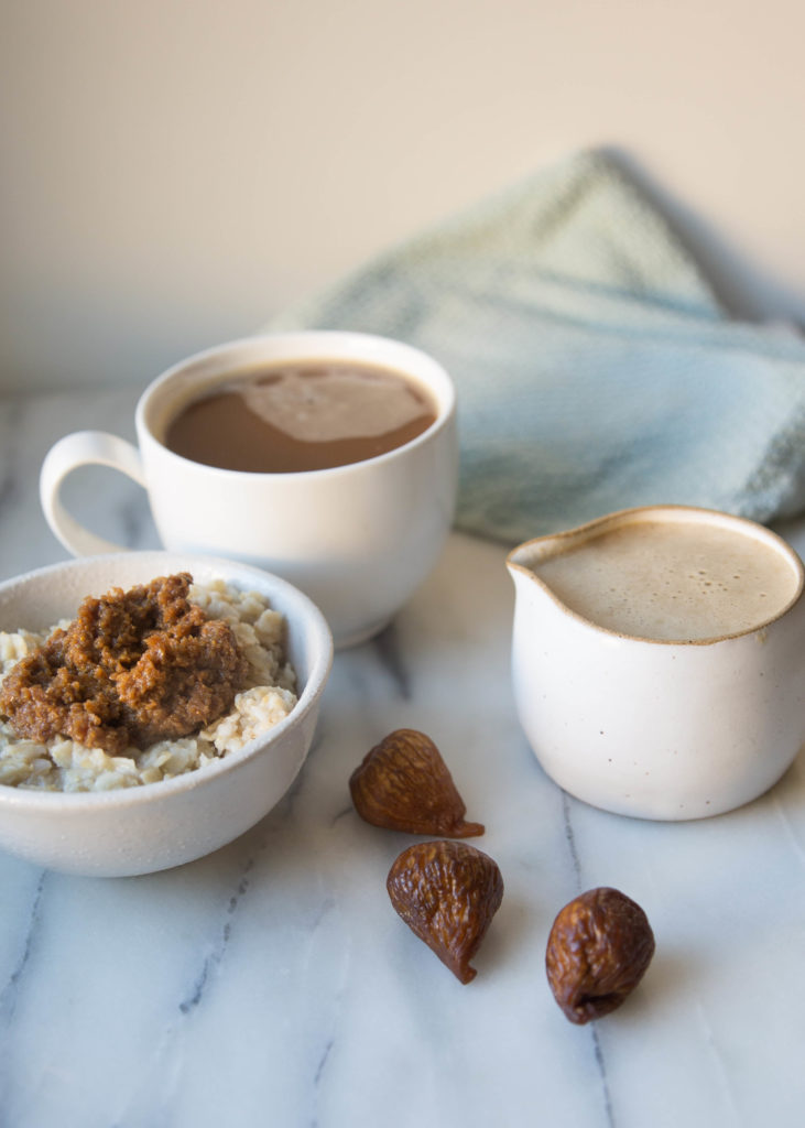 Bowl of oatmeal topped with fig milk jam by a coffee mug and pile of Orchard Choice Golden Dried Figs near a creamer full of Fig Holiday Coffee Creamer
