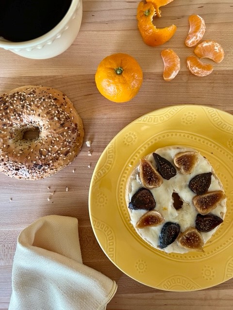 A plate of bagel with cream cheese and fruit