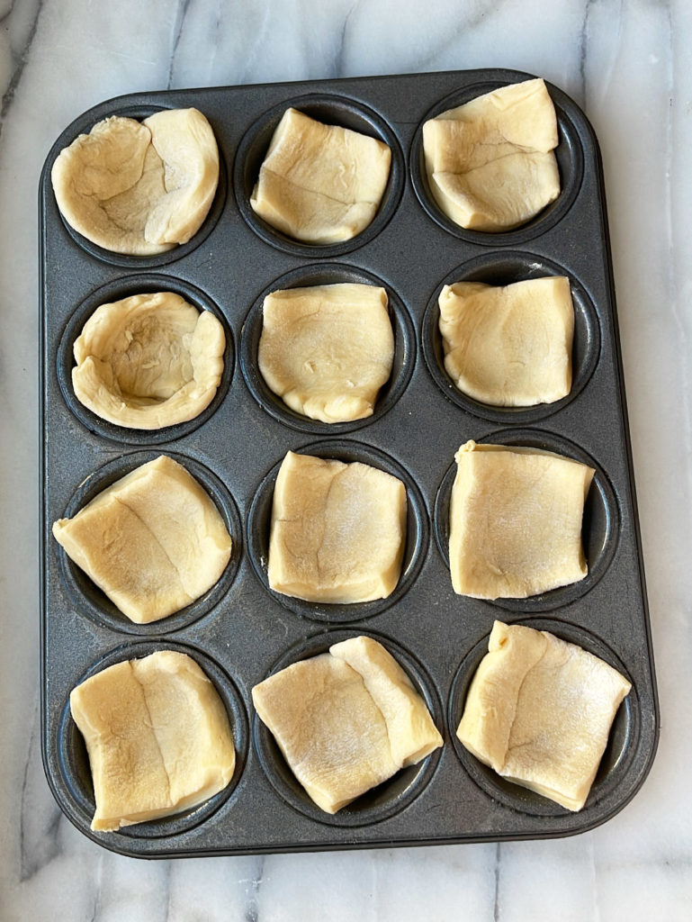 Raw crescent dough cut into 12 squares and placed into mini muffin tin