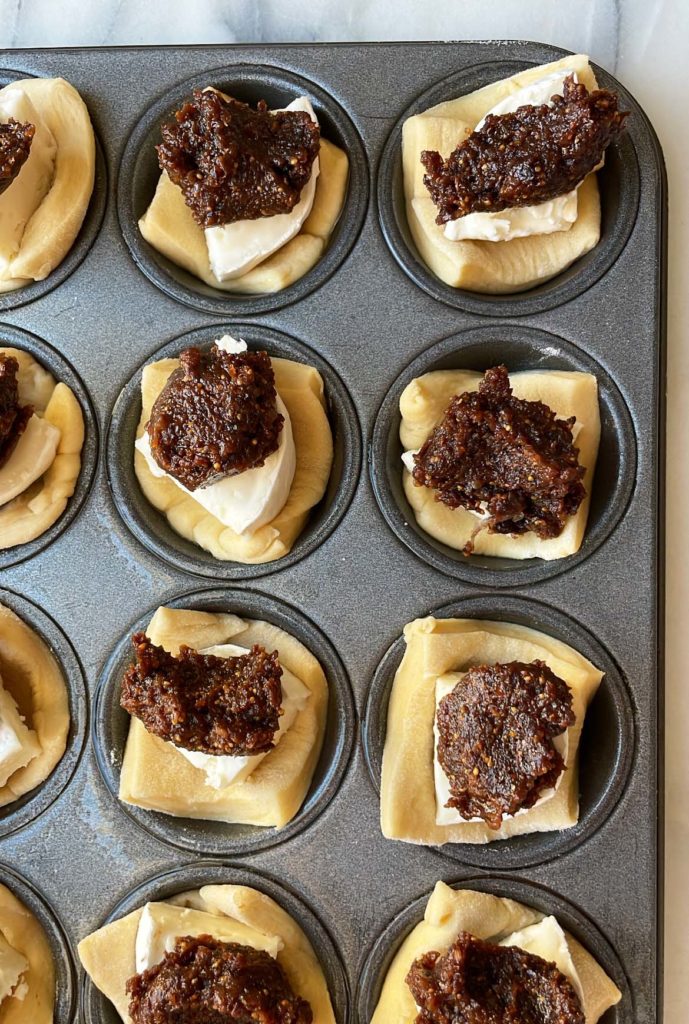 Mini muffin tin with baked brie bites topped with fig thyme jam