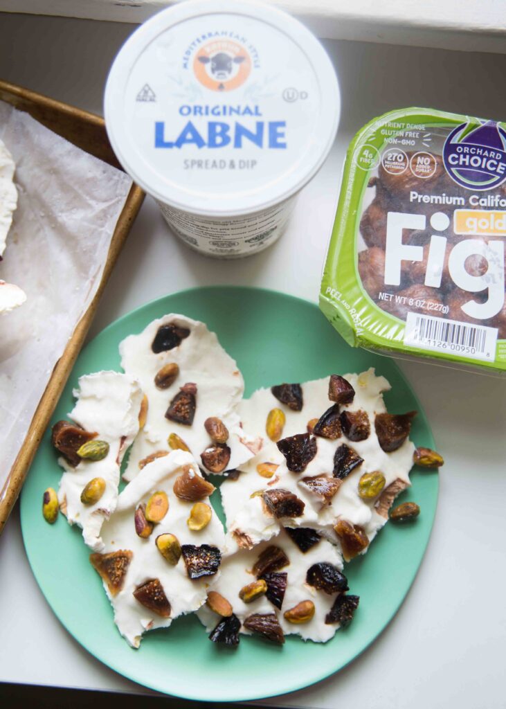 Plate of yogurt bark with a tub of labne and container of figs nearby