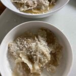 A bowl of ravioli with fig and goat cheese filling inside