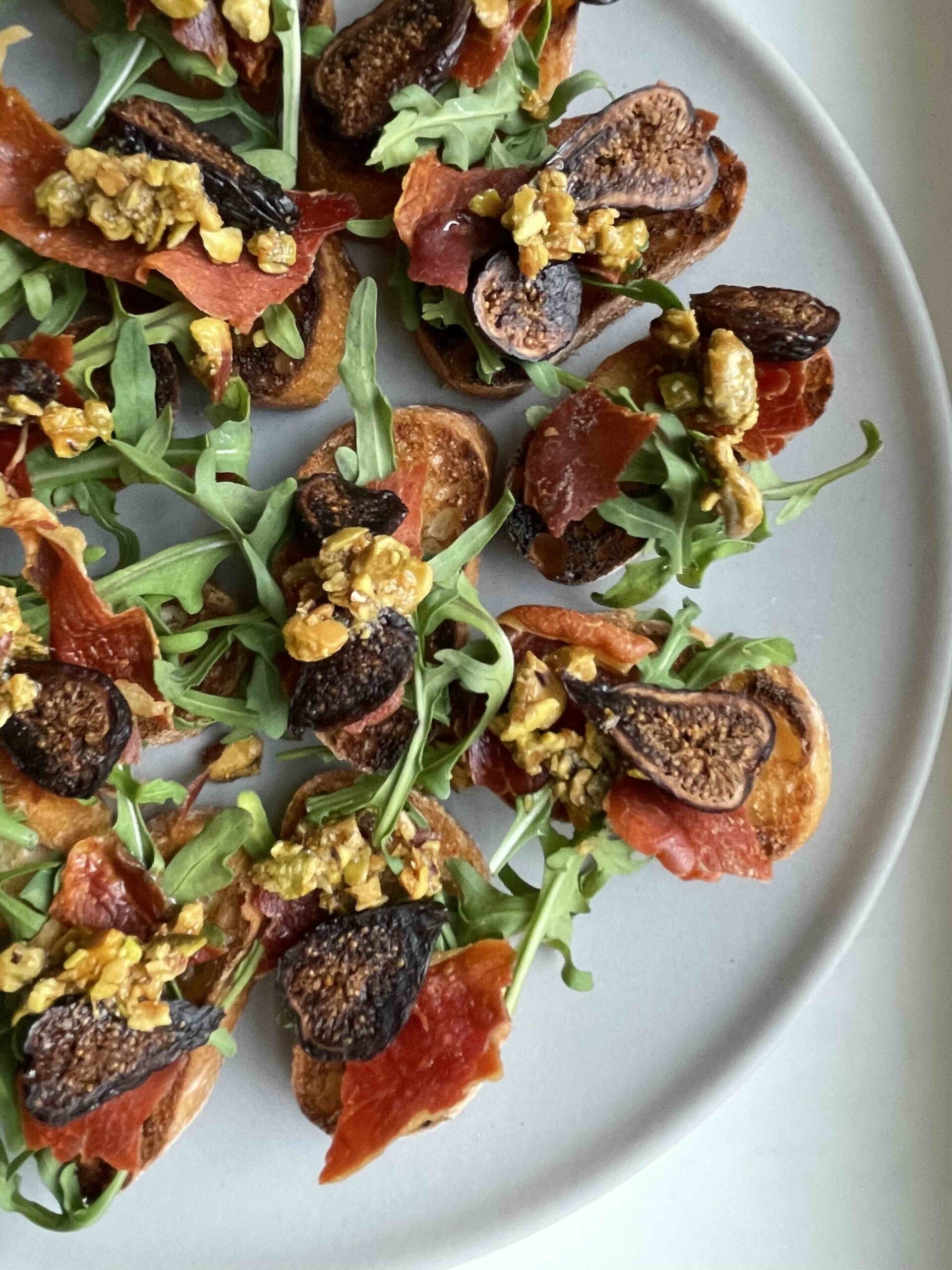 Grey plate with fig prosciutto crostini on top