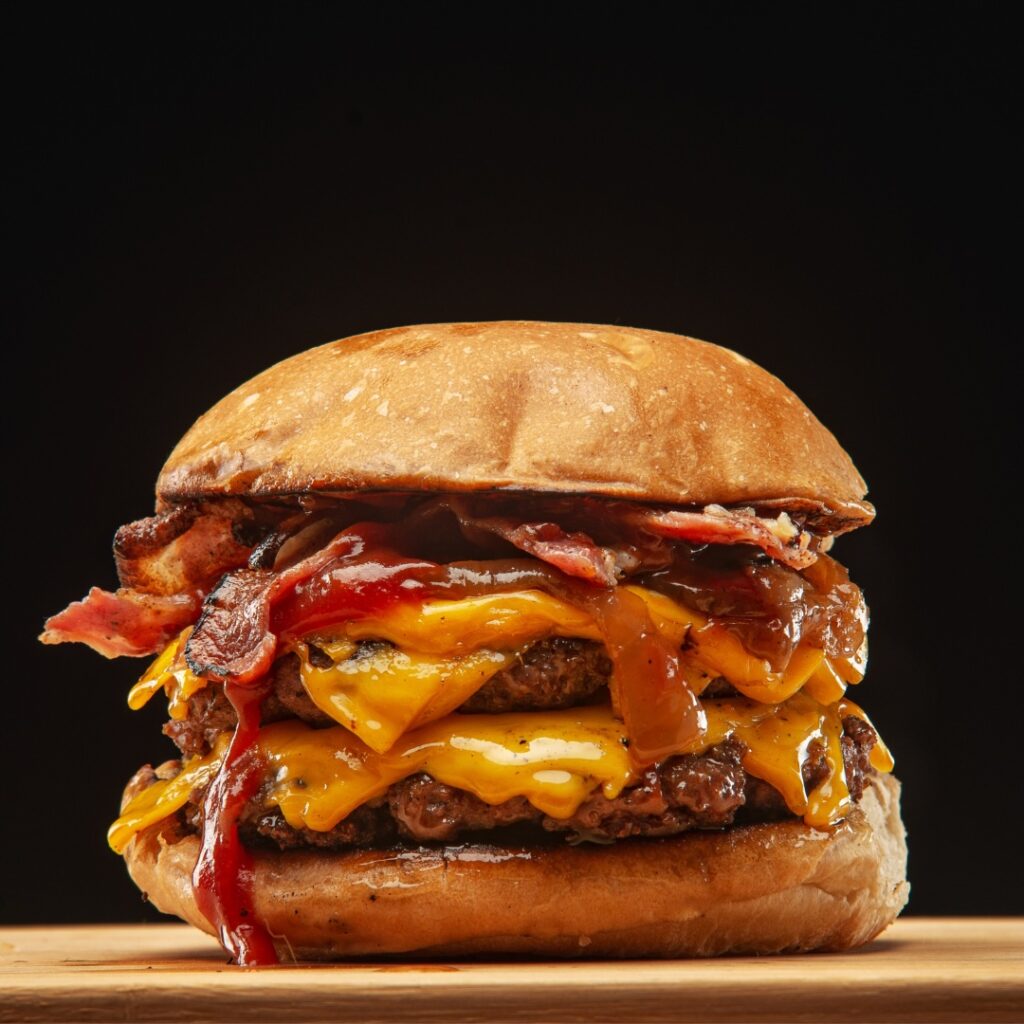 double decker bbq cheeseburger on a wooden cutting board