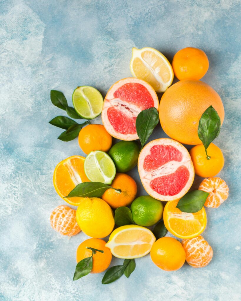 light blue backdrop with whole and cut open citrus on top